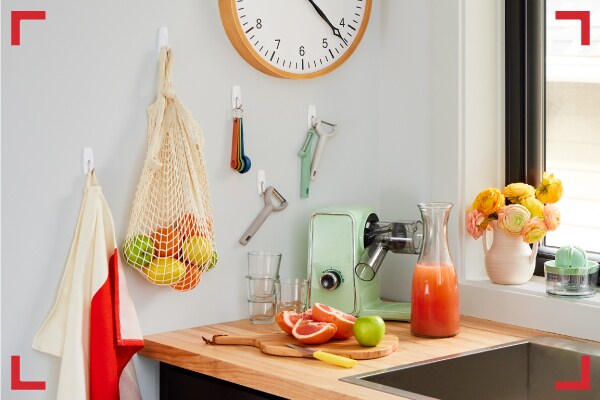 Cozinha organizada onde foram pendurados utensílios, frutas e avental com Ganchos Command®.
